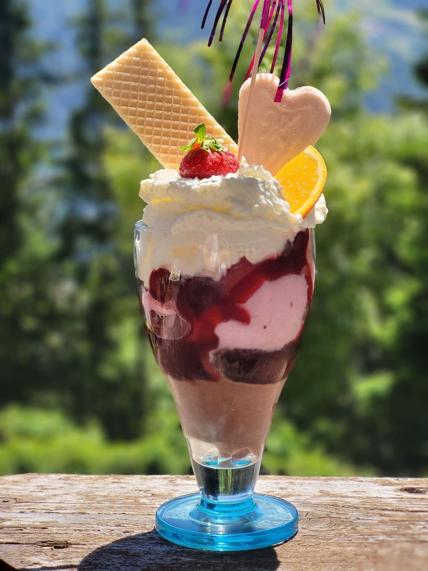 Hausgemachter Eisbecher mit Sahne, Erdbeere und Waffel auf der Terrasse des Café Obladis