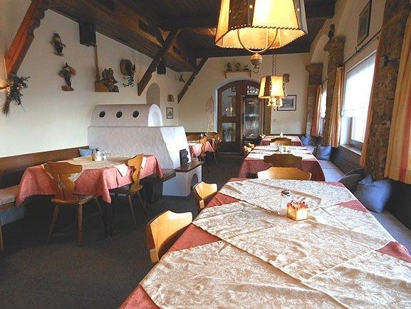 Rustikale Gaststube im Café Obladis mit weißem Kachelofen und gedeckten Tischen